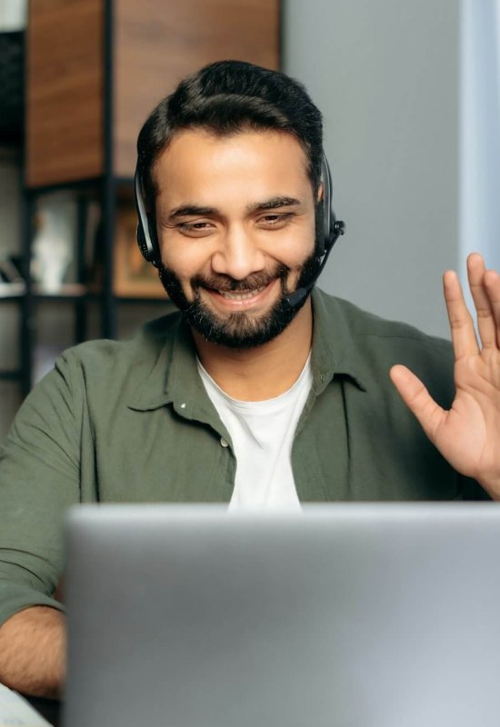 Positive attractive indian guy in headphones, hotline operator, support worker, online consultant