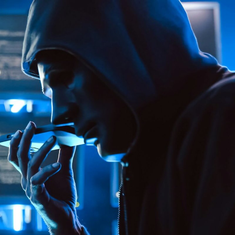 A hacker wearing a mask to cover his face is using computer to hack data to get ransom from victims.
