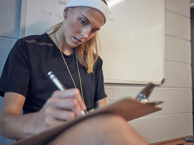 Woman, sport coach and clipboard writing of an athlete writing exercise schedule or plan. Personal