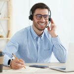 Smiling customer support service operator with hands-free headset working in office